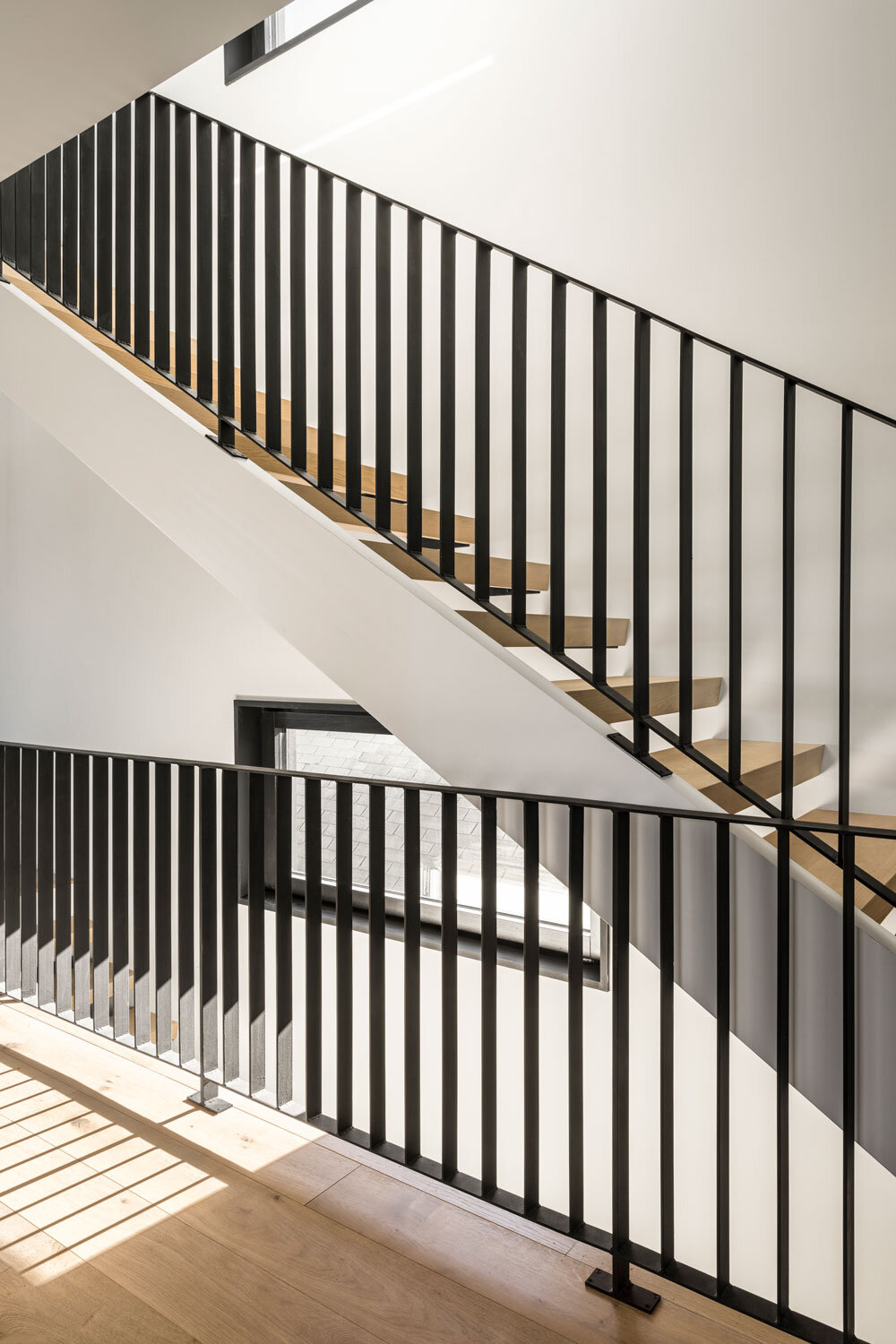 The open-tread oak staircase and steel banisters create clean, repeating lines.