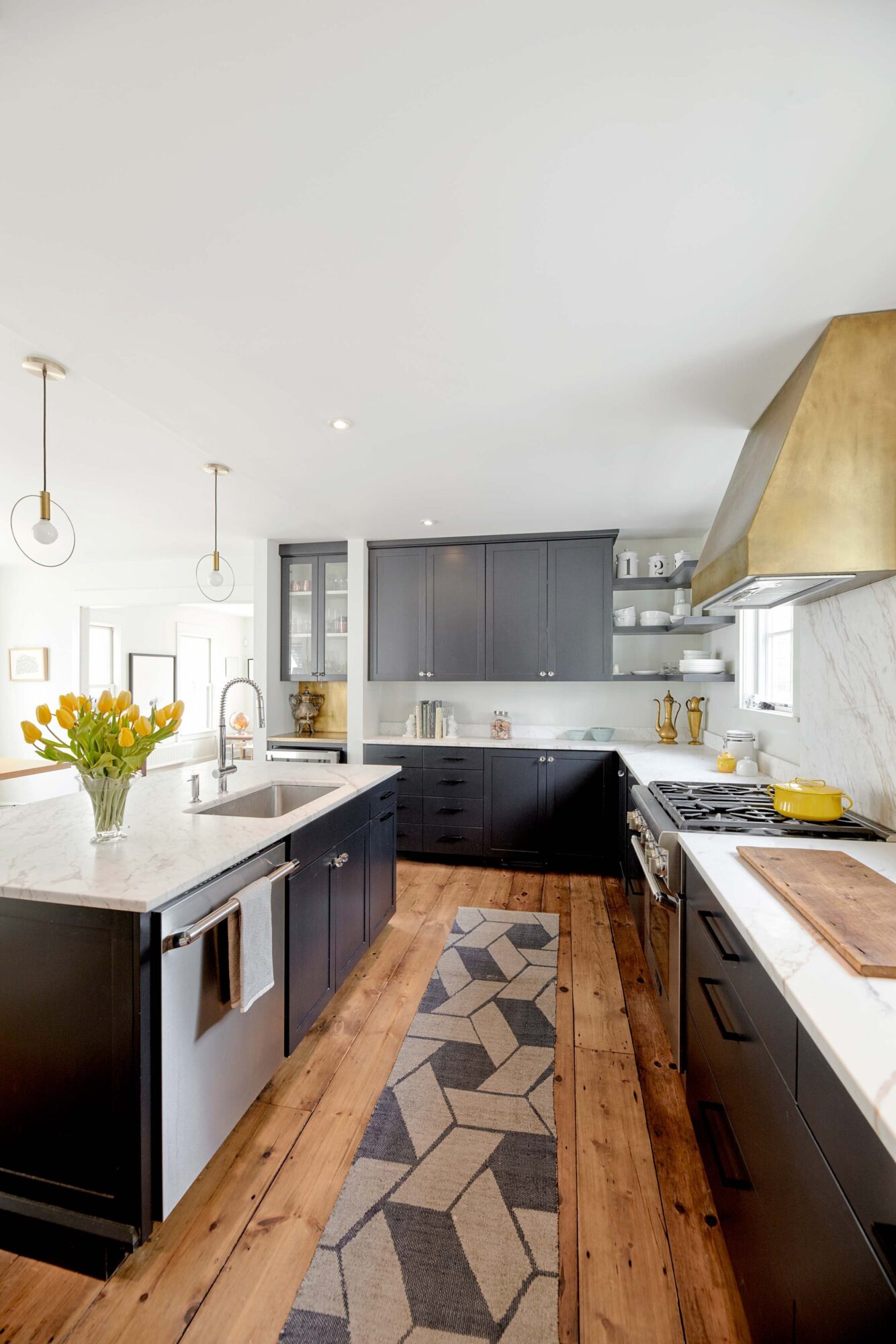  For the kitchen, Susan chose modern blue-based black cabinetry with builder Rick Romano and brassy details, as in the range hood and bar counter from Rusted Puffin Metal Works of Portland. 