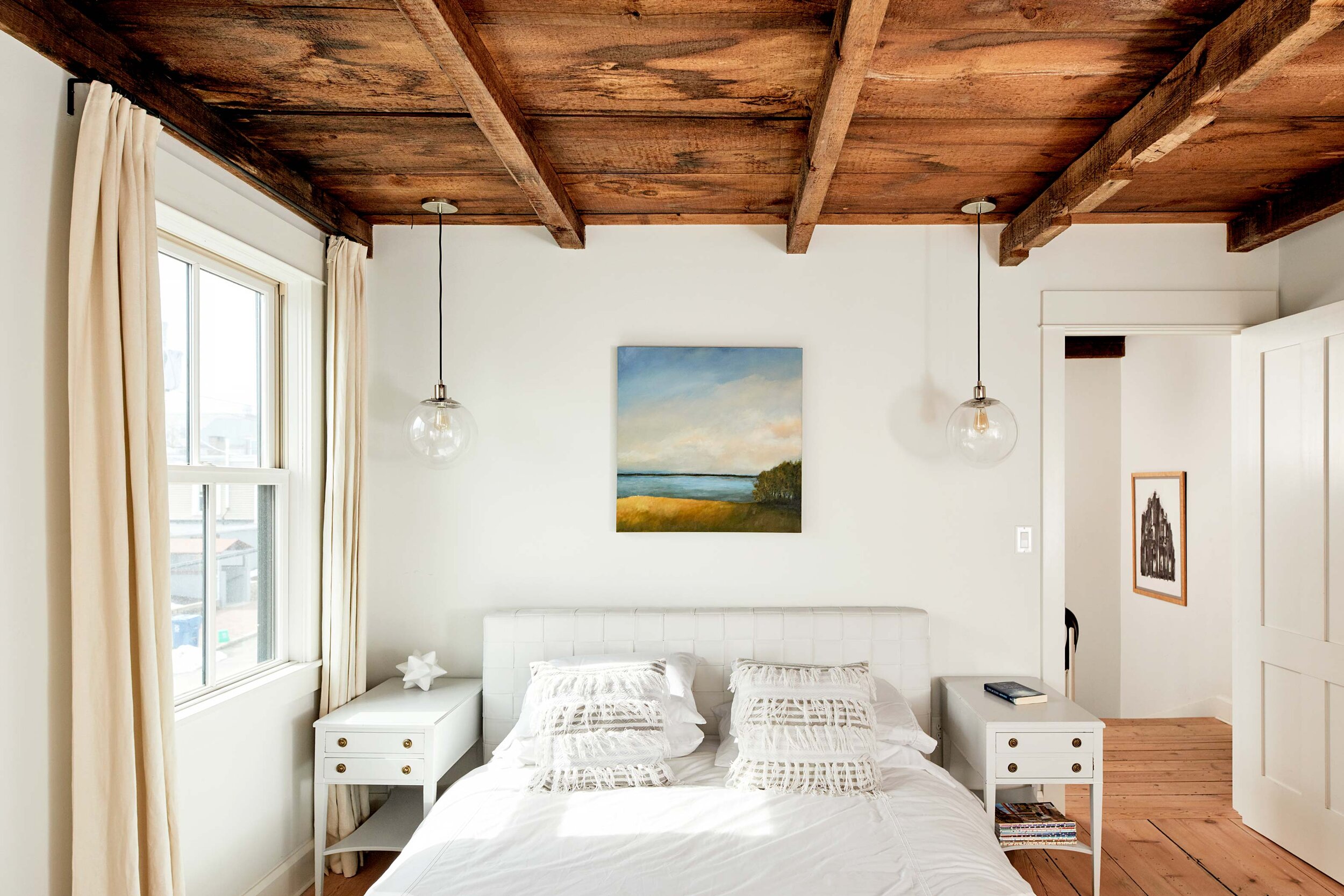  “The palette was always black, white, gray, and brown. Then I started bringing in color,” says Susan. Above the bed is a painting of Union River Bay by Lisa Creed. 