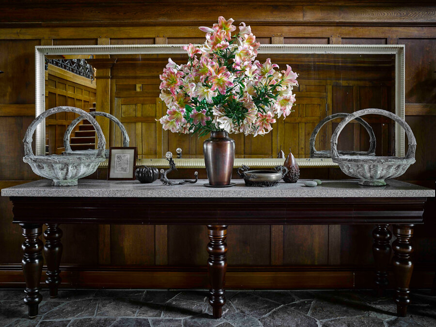 In the living room, a 1920’s French table topped in faux-bois is graced by a floral arrangement by executive creative director Kevin Sharkey.
