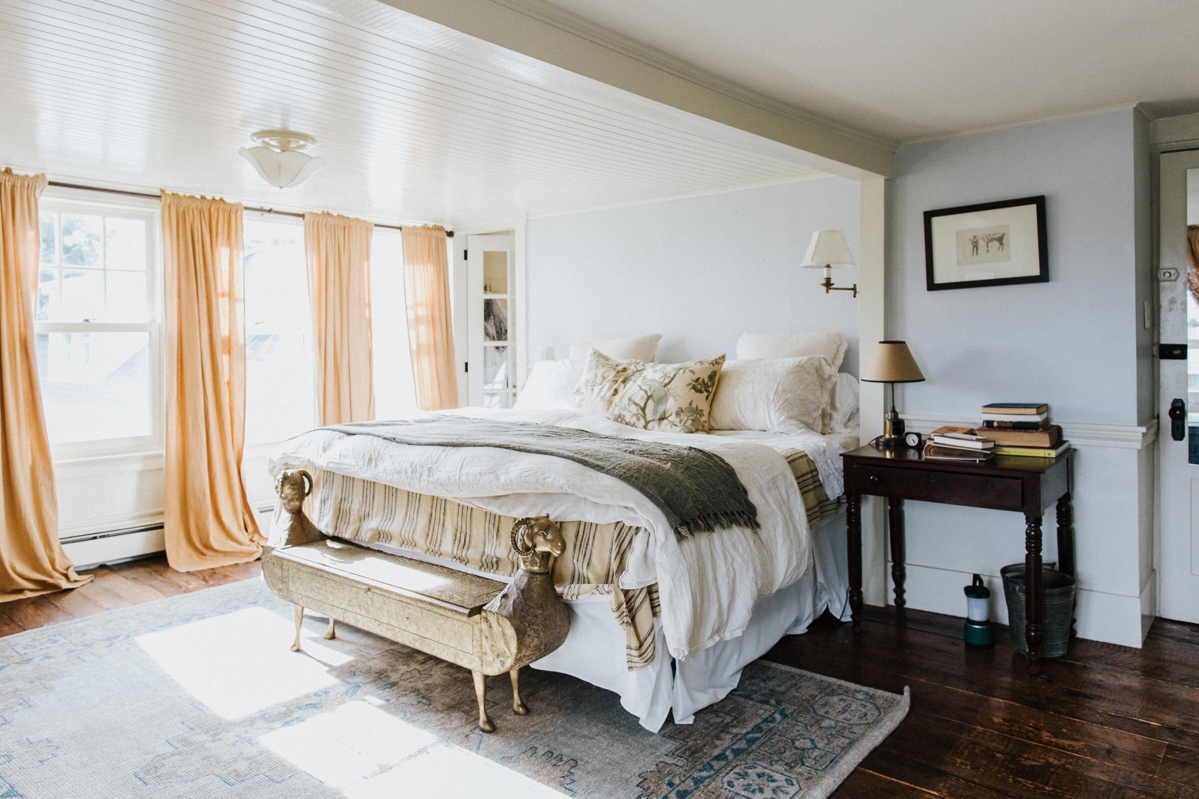  The couple’s light-filled bedroom has views out to the water. Wide-planked floors from the 1700s bring to mind the original purpose of their beloved home as a historic inn. 