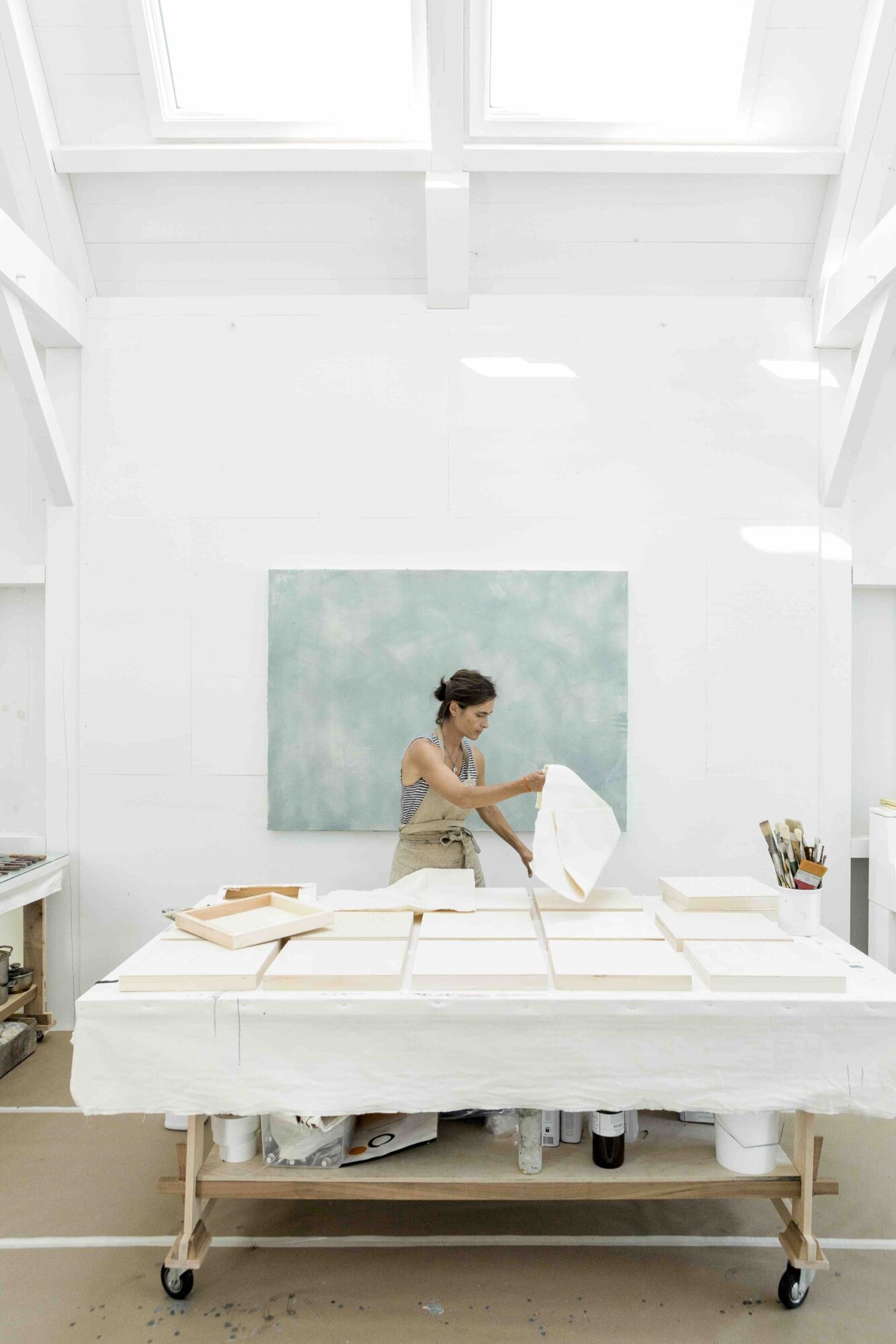 Betsy prepares canvases in her studio. Behind her is an encaustic work in progress.